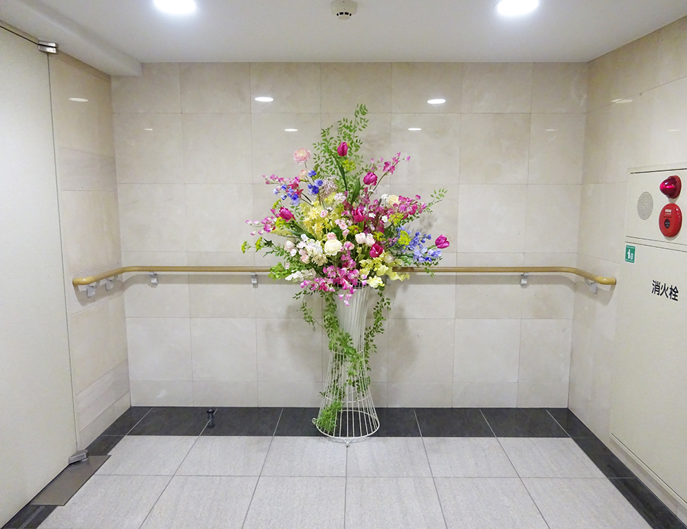 チューリップとスイトピーの色とりどりの春らしい大型スタンド花