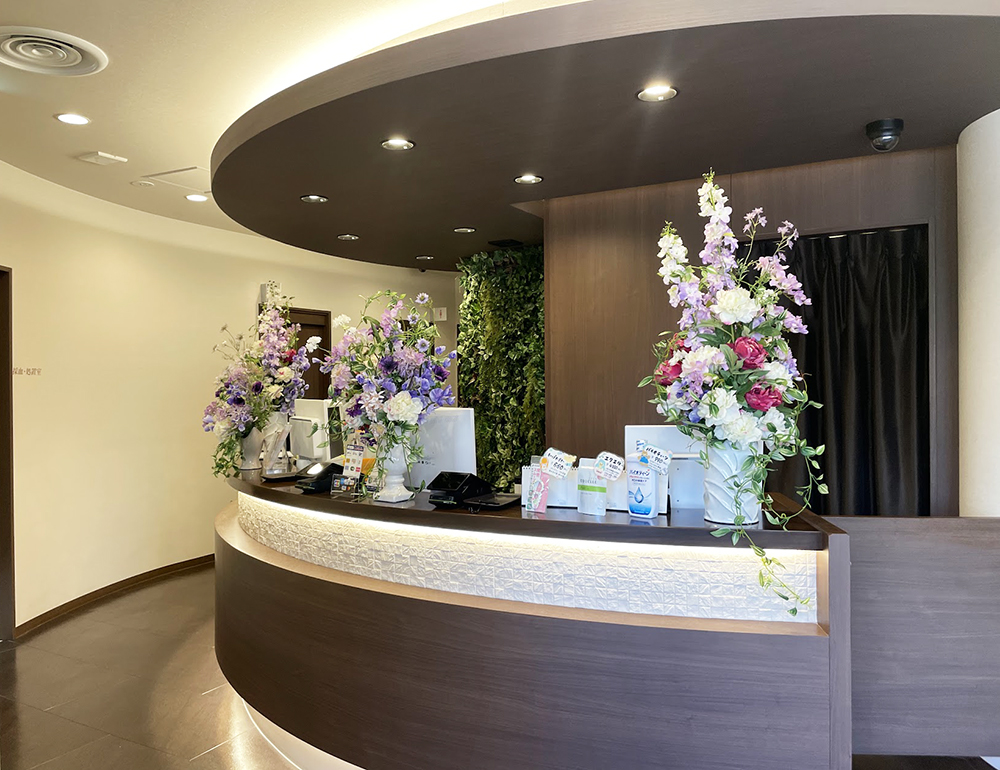 造花アレンジメントを受付カウンターに飾ってるクリニックの風景