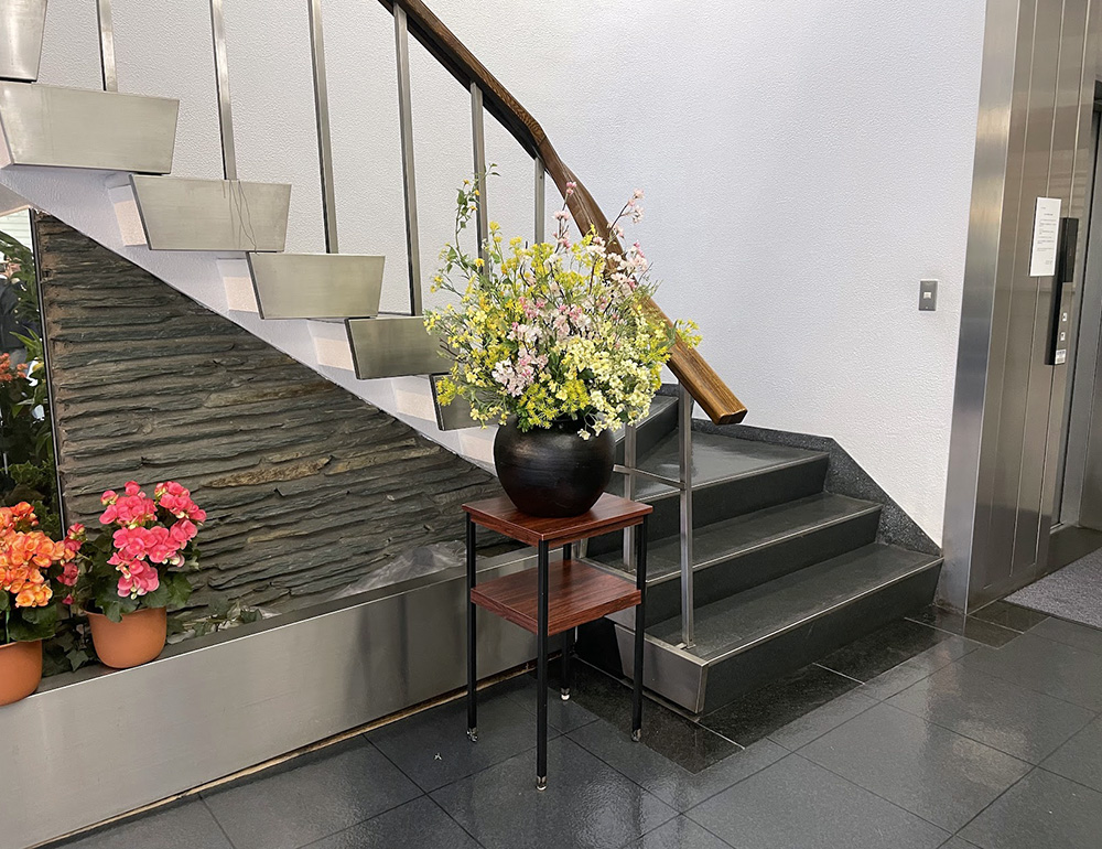 オフィスビルエントランスの花台に飾られた造花アレンジメント