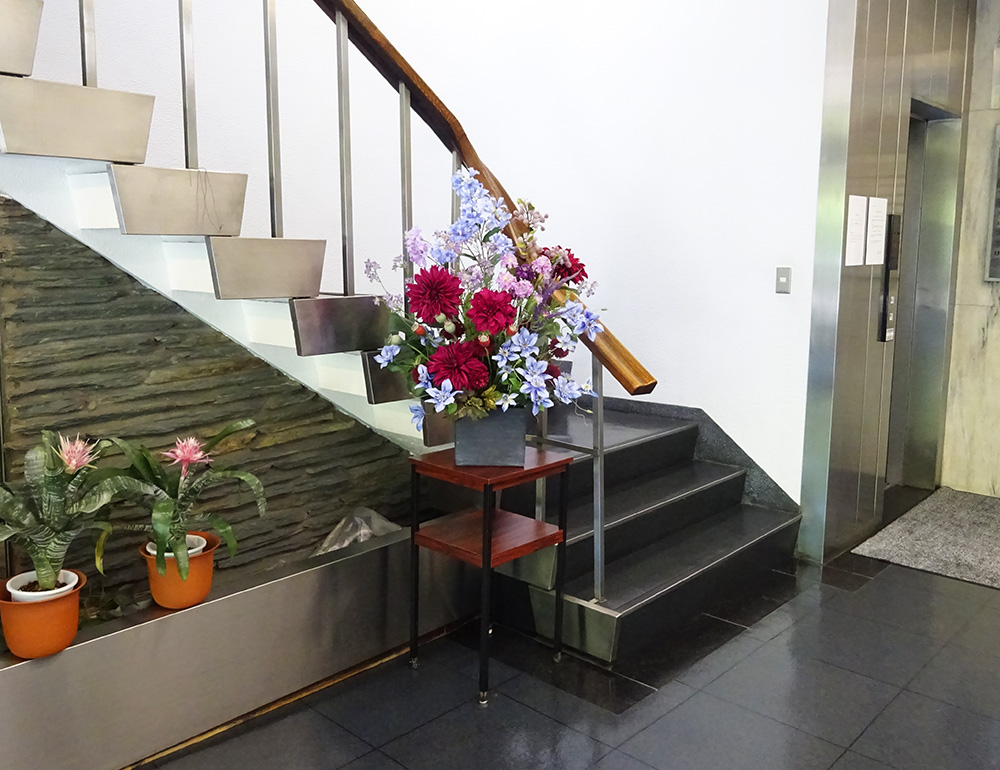 オフィスビルエントランスに飾られた造花アレンジメント