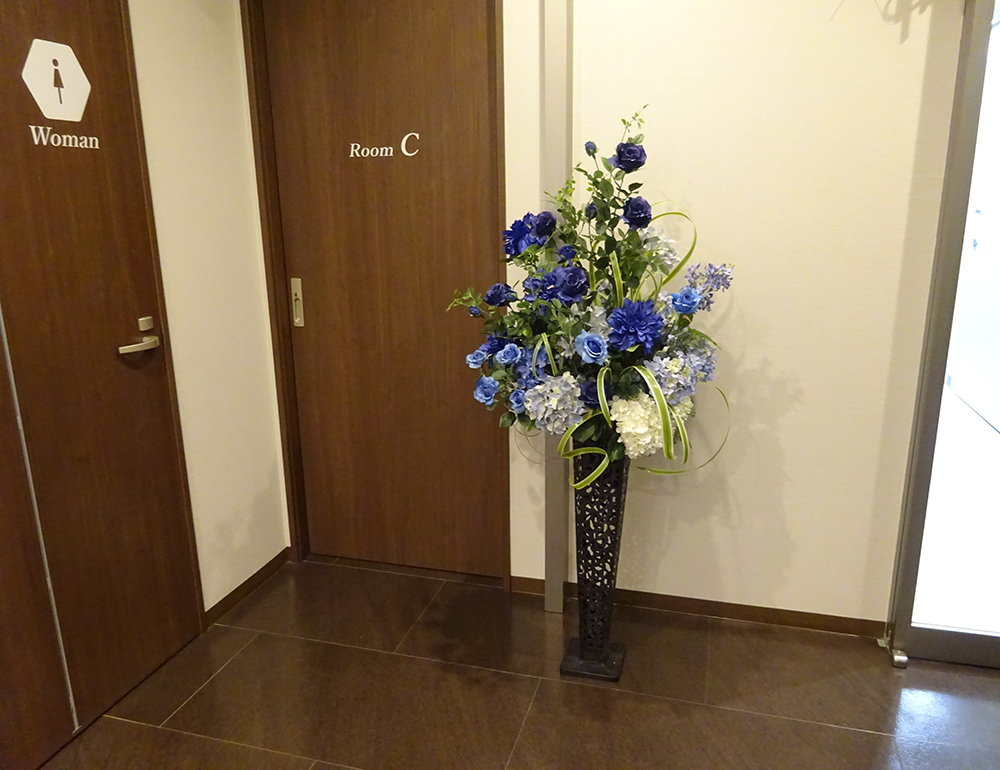 クリニック入口の夏らしいブルー系の造花レンタルフラワー